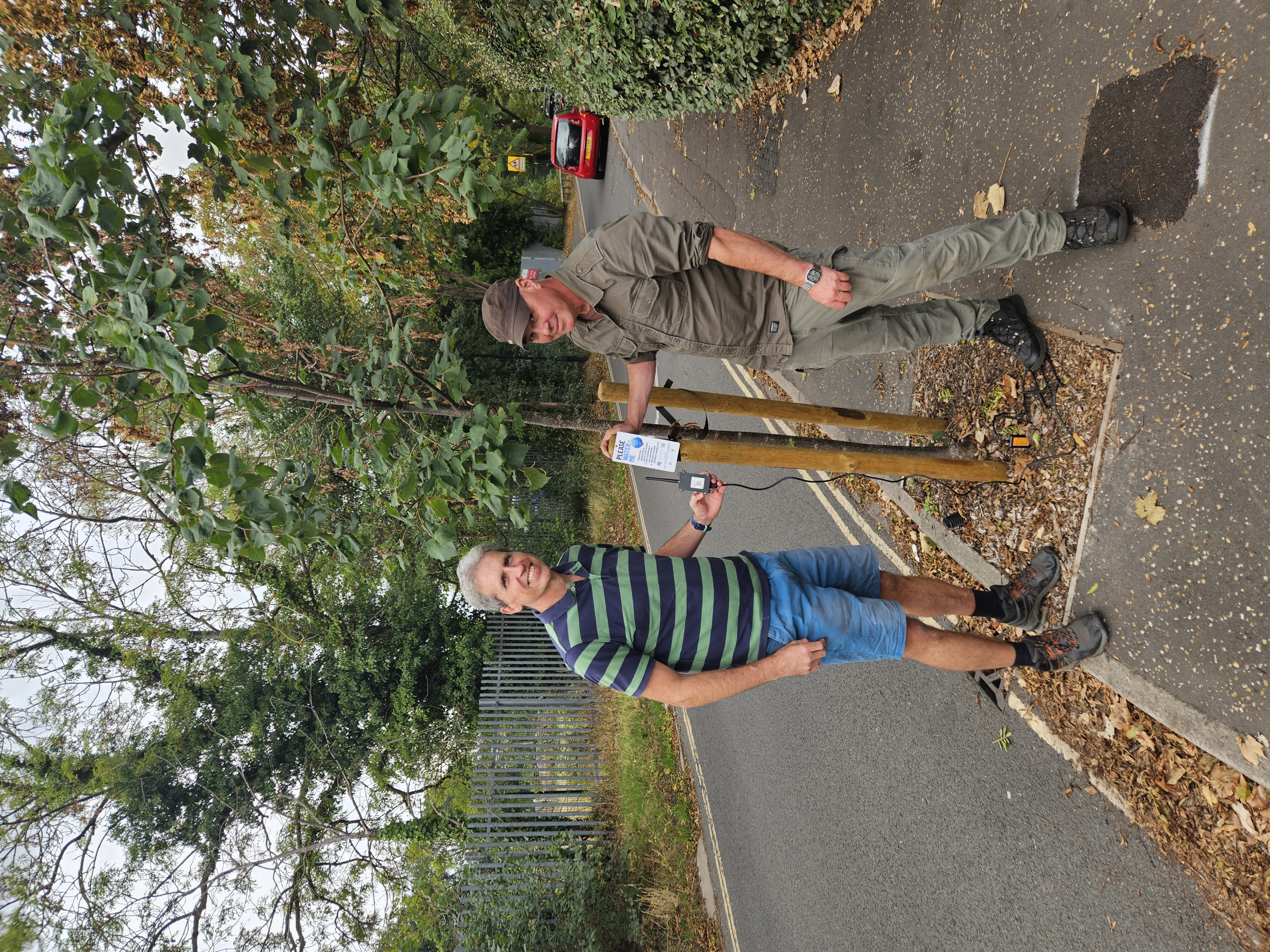 Jonathan Graham and Phil Paulo with a LoRaWAN sensor beside a young tree in Richmond